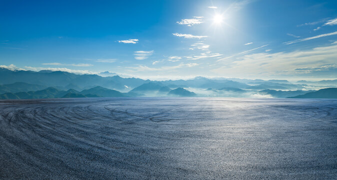 Empty asphalt race track with tire tracks and green mountain natural landscape in the morning