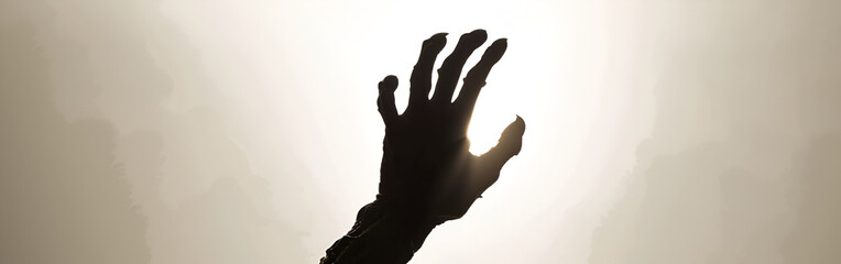 Silhouette of a reaching hand against a bright, hazy sky, conveying hope, struggle, or a plea.