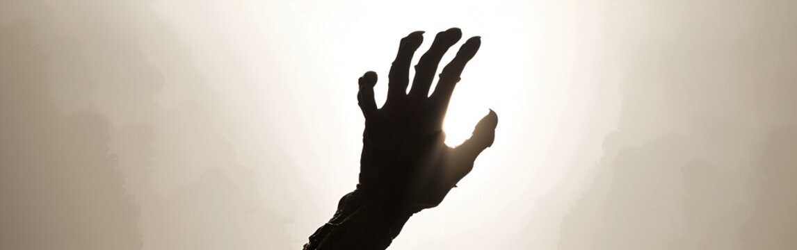 Silhouette of a reaching hand against a bright, hazy sky, conveying hope, struggle, or a plea. - Powered by Adobe