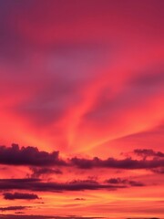 Clouds ablaze with orange, pink, and purple streaks over a distant silhouette of hills,  scenic,  colorful