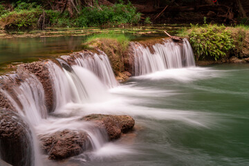 Cascading Beauty: A serene view of a small waterfall gracefully cascading over rocky formations, creating a tranquil atmosphere, emphasizing the beauty of water and nature's artistry.