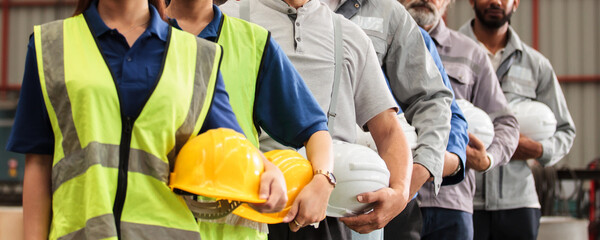 Engineers and factory workers standing in line with safety helmets