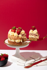 Pulling a slice of strawberry cake on red 