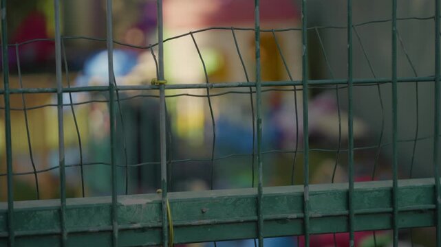 Kindergarten or playground with toys and cribs, focus to the foreground wire fence. school safety, restricted access, supervision standards, closures, investigations. lonely, sad, harassment, abuse