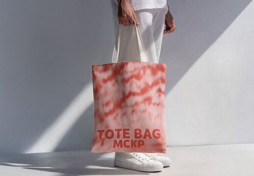 This mockup features a stylish white tote bag being held by man against a clean, minimalistic background.