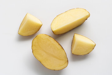 Four slices of fresh potato arranged on a white background, showing the smooth texture and yellow flesh.