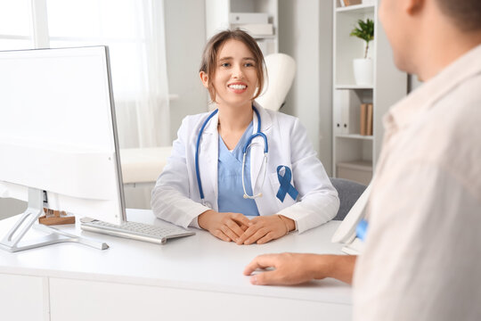 Female doctor with blue ribbon and male patient in clinic. Prostate cancer awareness concept