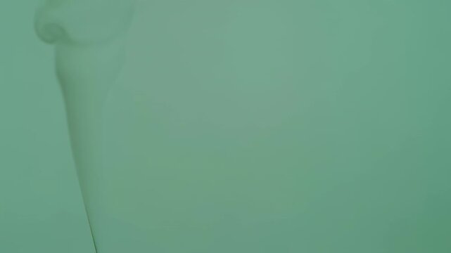 An abstract, curved form of light hue against a green gradient