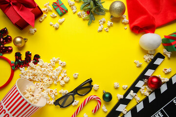 Obraz premium Frame made of popcorn, movie clapper, 3D glasses, gifts and decorations on yellow background. Christmas movie