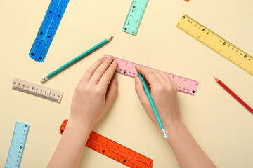 Female hands with pencils and rulers on beige background
