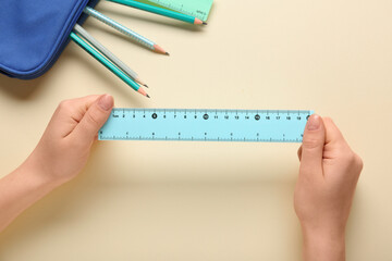 Female hands with rulers, pencils and case on beige background