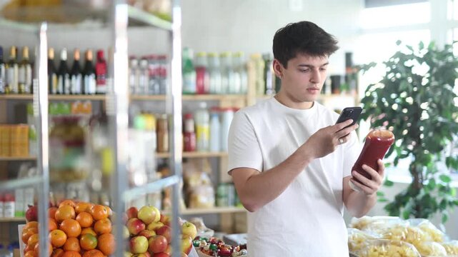 Male buyer checks suitability - scans QR code on jar of ketchup label in a grocery store. High quality 4k footage