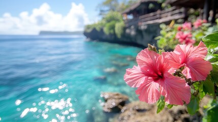 A vibrant pink hibiscus flower blooms in the foreground by a tranquil blue sea, with lush greenery and a rocky coastline in the background, Ideal for travel, relaxation, or nature-themed projects,