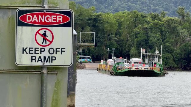 Vehicle Ferry Approaches Riverbank with Safety Warning Sign