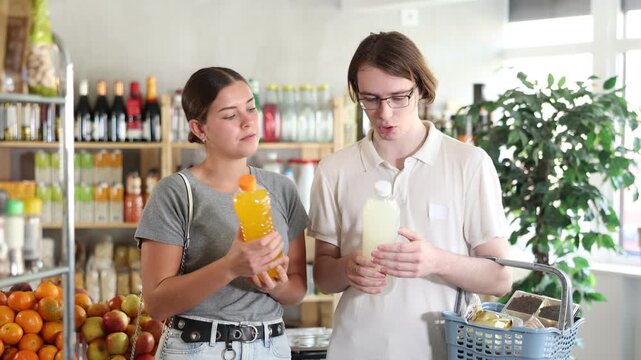 Husband and wife choose drinks, juices and compotes in a European supermarket. High quality 4k footage