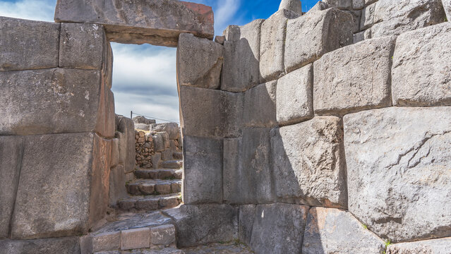 The ancient Inca fortress Sacsayhuaman. A fragment. Stone gates. The steps go up the hill.  Polygonal ashlar masonry walls. Blue sky, clouds. Peru. Cusco. 