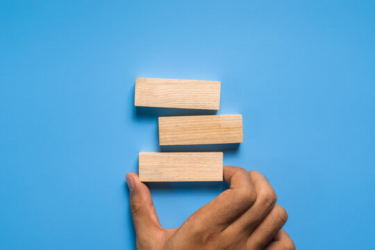 male hand put three blank wooden blocks isolated on blue background