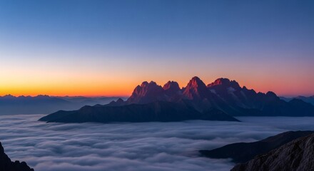 Mountains peak above clouds at sunrise/sunset with colorful sky