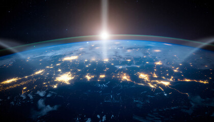 Obraz premium Stunning view of Earth from space at night with glowing city lights and a bright sunbeam breaking through the atmosphere.