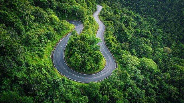 A drone view of a joyride through winding mountain roads surrounded by lush greenery