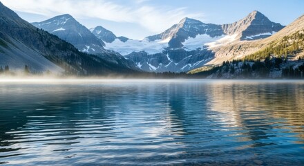 Serene, early morning view of a pristine lake reflecting snow-capped mountains and a clear sky