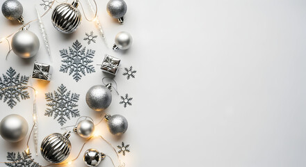 Obraz premium Elegant holiday flatlay of silver and white ornaments with snowflake confetti and warm string lights perfect for seasonal banners, festive blog headers, and holiday product pages that emphasize a refi