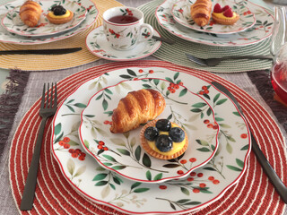 Table setting with bright tableware, berries, and twigs. Dessert on plate. Aesthetics and lifestyle. Home design. 