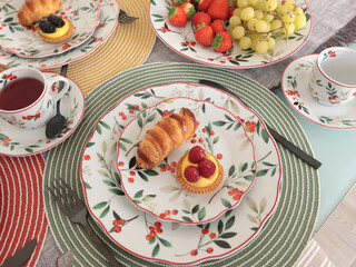 Table setting with bright tableware, berries, and twigs. Dessert on plate. Aesthetics and lifestyle. Home design. 