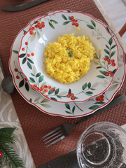 Table setting with bright tableware, berries, and twigs. Saffron risotto on plate. Traditional Italian food. Aesthetics and lifestyle. Interior design. 