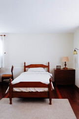 image of Wooden bed and furniture in a hotel room with white sheets and pillows, vintage bed room decor