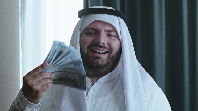 An arrogant Arab with a wad of cash dollars laughs and looks at the camera