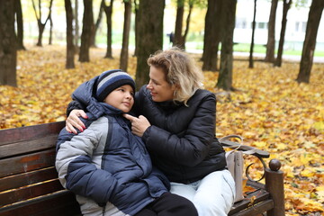 A woman meets her son in the park on a beautiful autumn day.