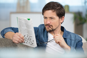 man contemplating clue in puzzle book