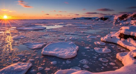 A vibrant sunset casts golden light over an icy seascape, snow and ice