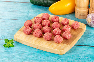 Raw beef meatballs over board