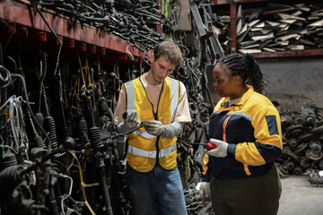 African American and Caucasian technician or engineer checking car part with car part background	