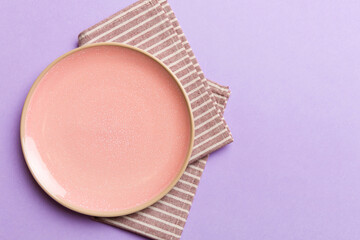 Top view on colored background empty round pink plate on tablecloth for food. Empty dish on napkin with space for your design
