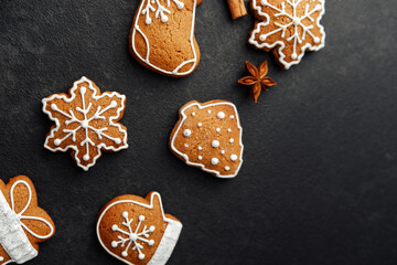 Sweet holiday cookies with snowflake icing decorations arranged on a dark textured background