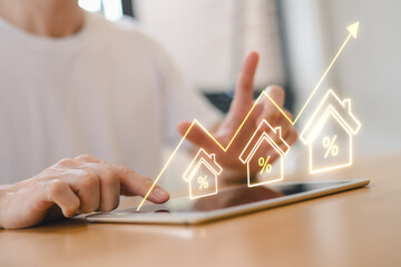 Real estate investor analyzing property growth and interest rate trends on tablet with digital graph interface. Housing market investment financial technology concept.