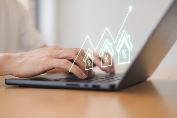 Real estate investor analyzing property growth and interest rate trends on tablet with digital graph interface. Housing market investment financial technology concept.