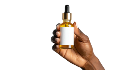 Hand holds amber oil bottle with blank label on dark backdrop