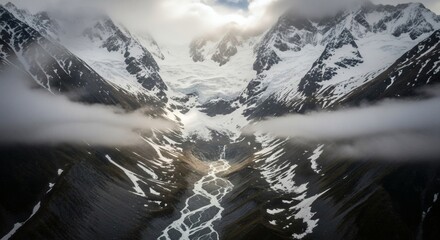 Aerial view of a glacial valley carved between towering snow-capped mountains under a cloudy sky
