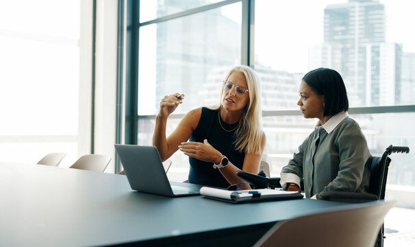 Two businesswomen discussing plans in a modern office setting - Powered by Adobe