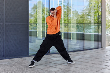 Naklejka premium European young man dressed in a stylish image dances free electro dance