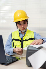 Asian female engineer uses a laptop or notebook to print barcode stickers on a barcode printer.