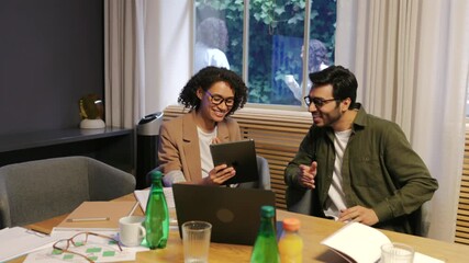 Smiling diverse coworkers discussing project and sharing ideas with digital tablet in modern office showing teamwork communication and creativity in positive corporate environment - Powered by Adobe