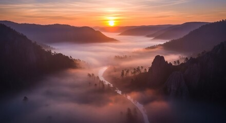 Aerial view of a river winding through valley, shrouded in mist, bathed in warm sunset hues