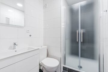 Modern bathroom interior combining white tiles and frosted glass shower