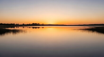 Obraz premium Serene panoramic view of a lake reflecting the warm colors of a sunset sky