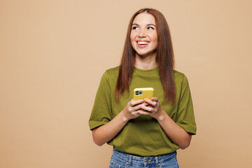 Young happy woman she wears olive green t-shirt casual clothes hold in hand use mobile cell phone...